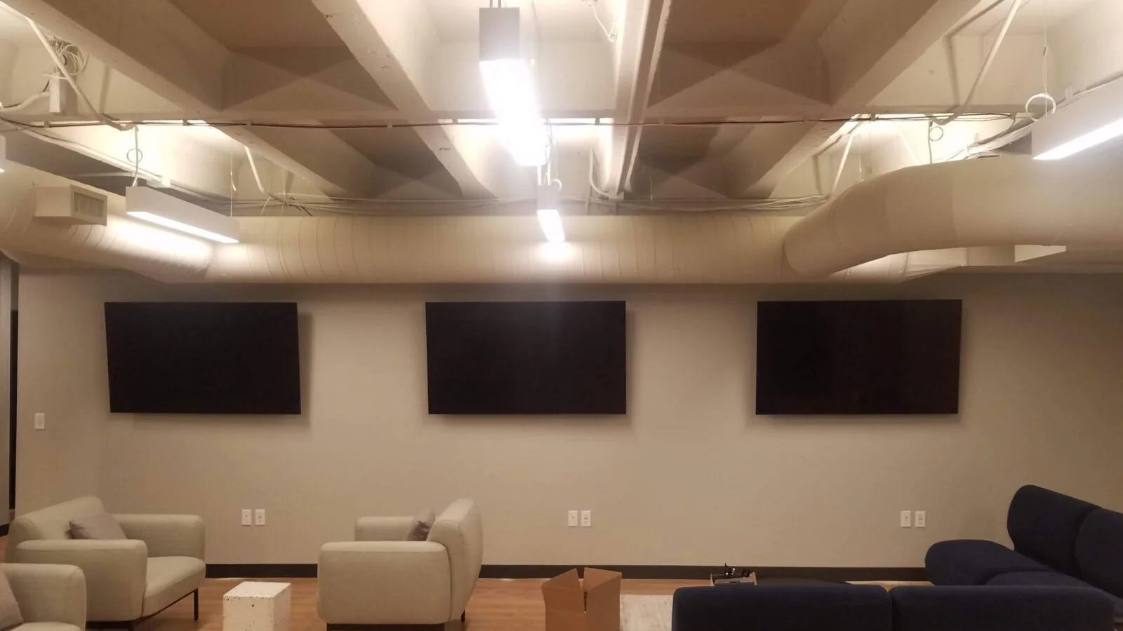 Three displays aligned across a finished media room wall