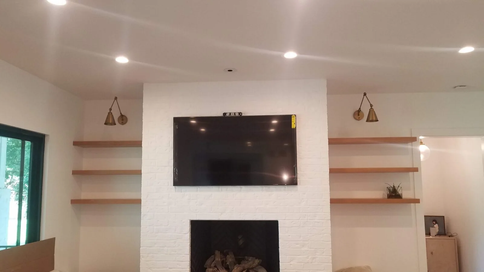Securely mounted TV above a fireplace between built-in shelves