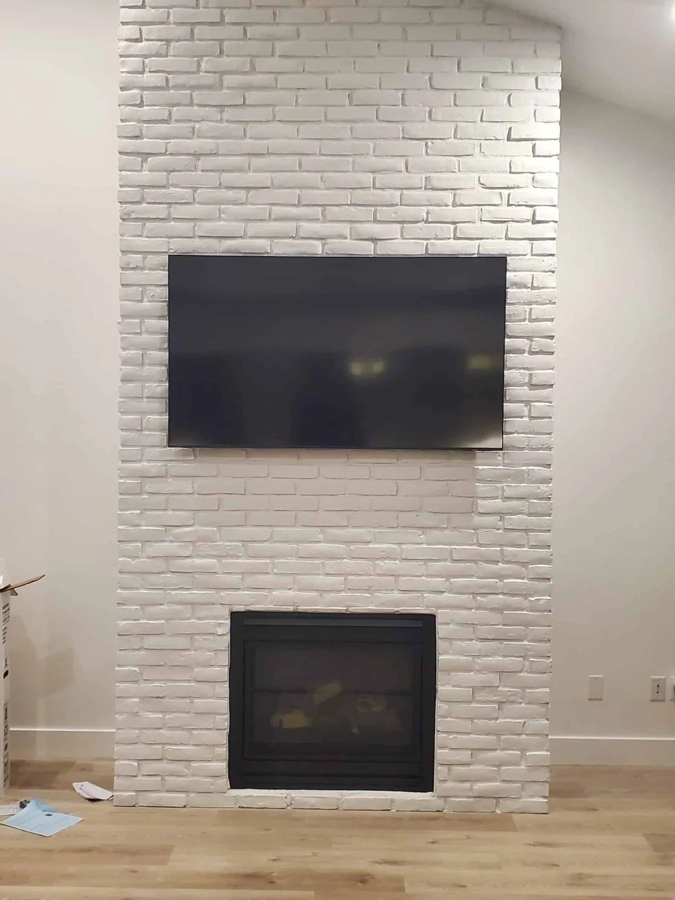 TV mounted above a black fireplace on a white brick feature wall