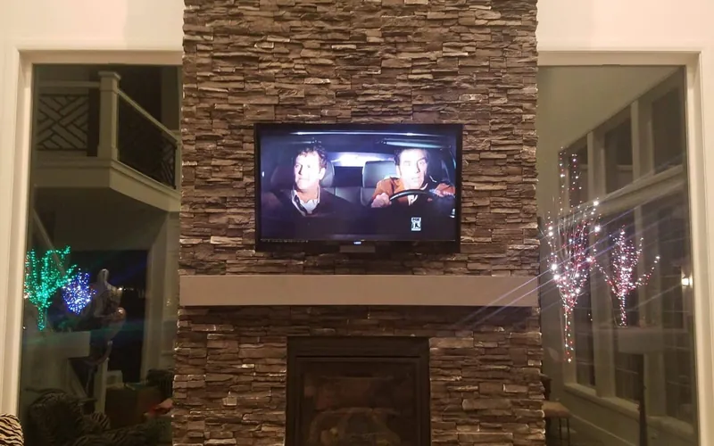 Television mounted above a stone fireplace