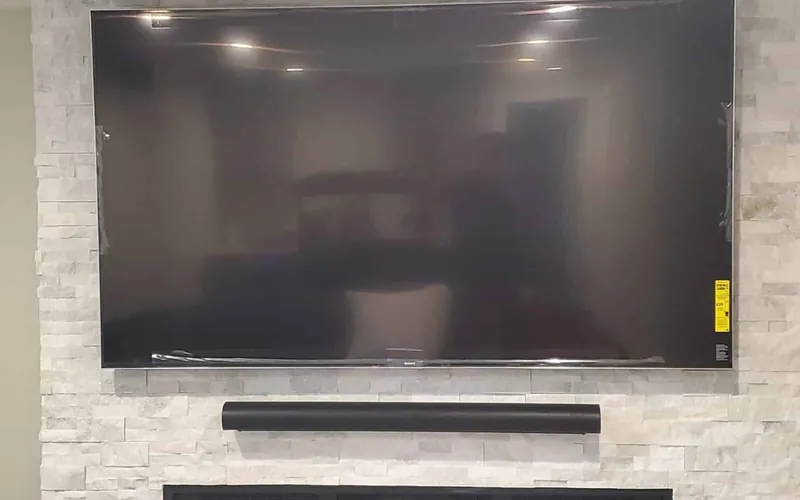 Large wall-mounted television with a soundbar installed directly below