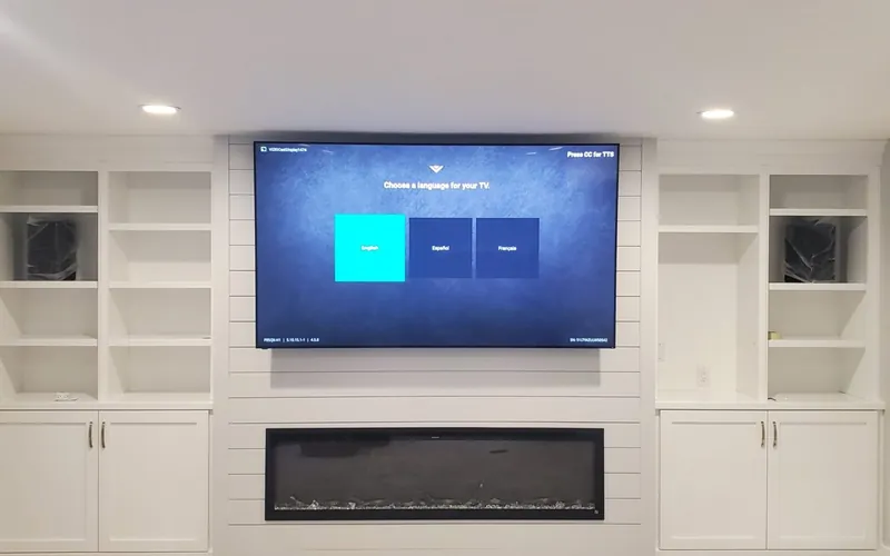 Wall-mounted television above a modern fireplace with built-in shelving